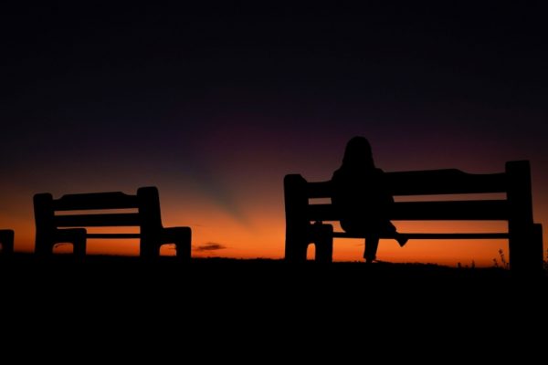 Woman sillouetted on bench at sunset