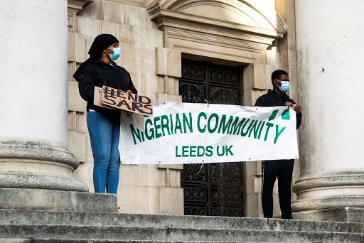 Two protesters holding a banner reading 'Nigerian Community Leeds UK'